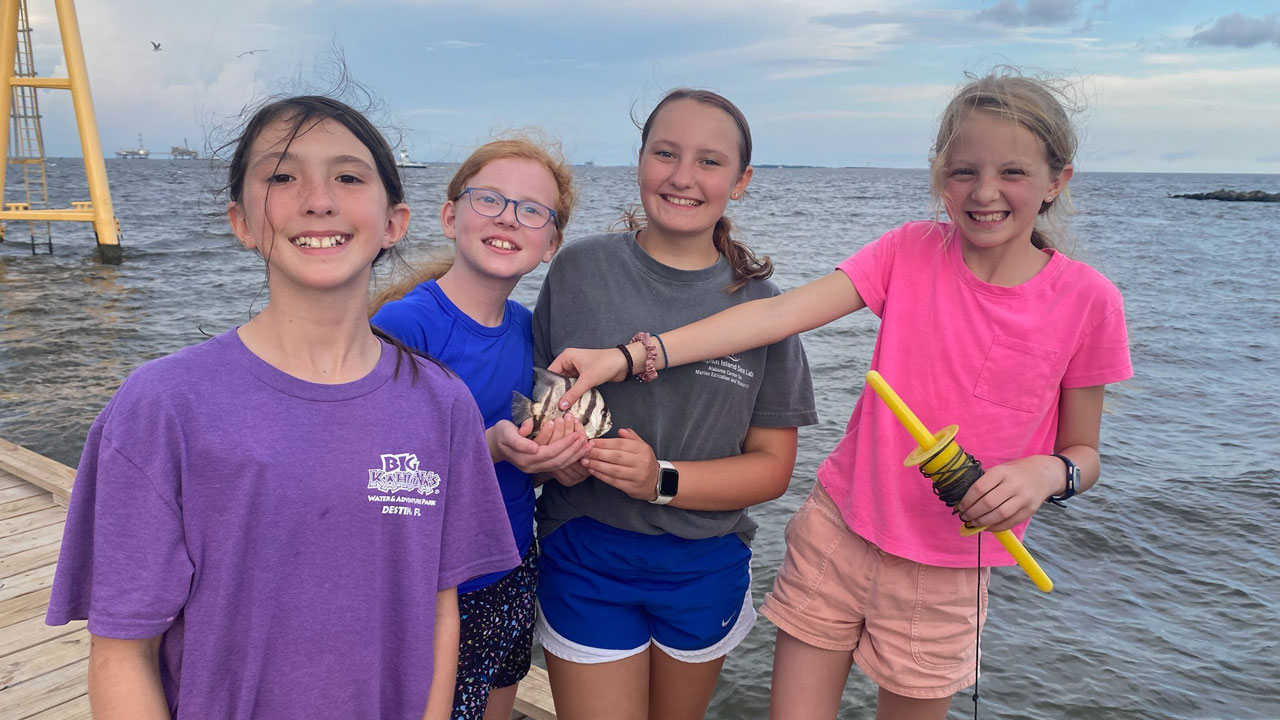 four girls on dock with fish