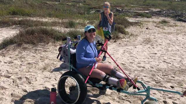 Two students on the beach, one in a beach-wheelchair