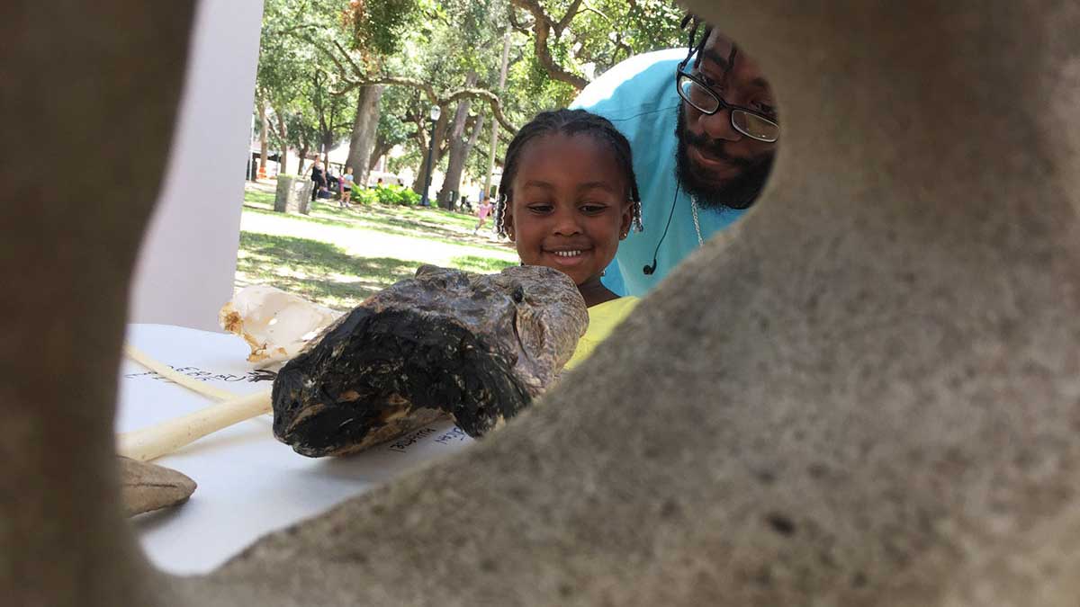 Child smiling at marine samples from BayMobile outreach