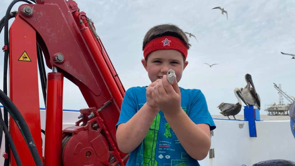 A young boy holds a fish.