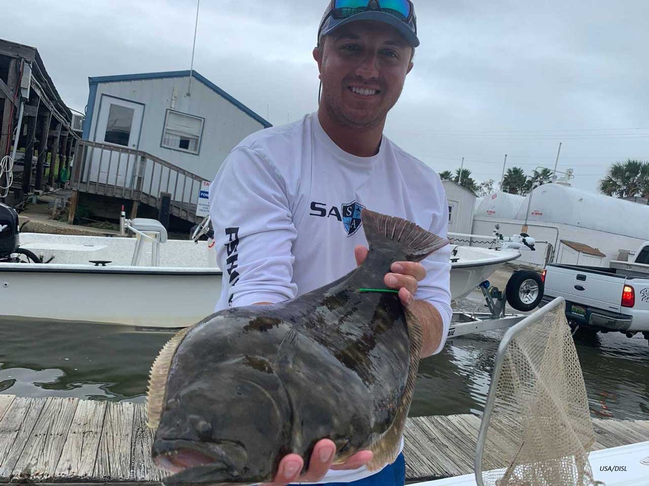 Dylan Kiene holds flounder as part of graduate research.